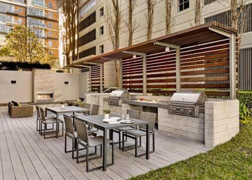 A patio with a table and chairs and a grill.
