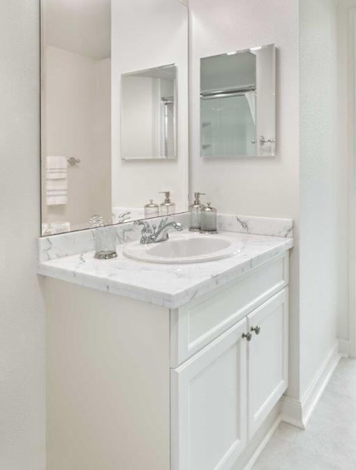 A white bathroom with a sink and mirror.