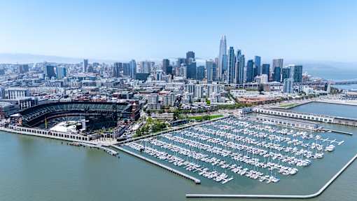 A cityscape with a marina and a stadium.