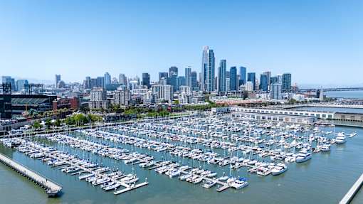 A marina filled with lots of boats in front of a city skyline.