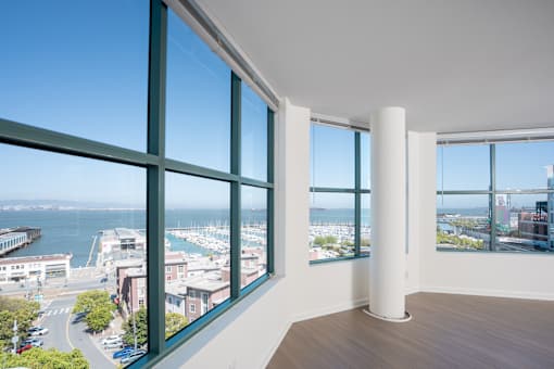 A room with a large window overlooking a harbor.