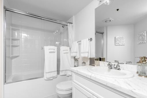 A white bathroom with a toilet, sink, and shower.