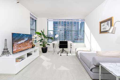 A modern living room with a television, a couch, a desk, and a plant.