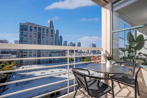 A balcony with a table and chairs overlooking a cityscape.