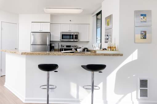 A kitchen with a bar stool in front of a counter.