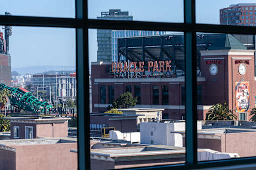 A view of a cityscape through a window with a building named Dodger Park visible.