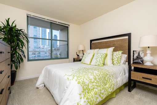 A bedroom with a large bed and a potted plant.