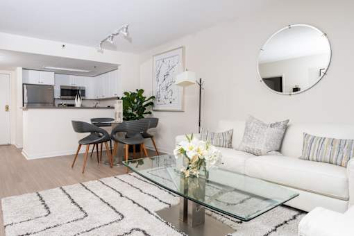 A modern living room with a glass coffee table and a white sofa.