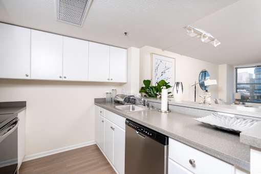 A kitchen with white cabinets and a grey countertop.
