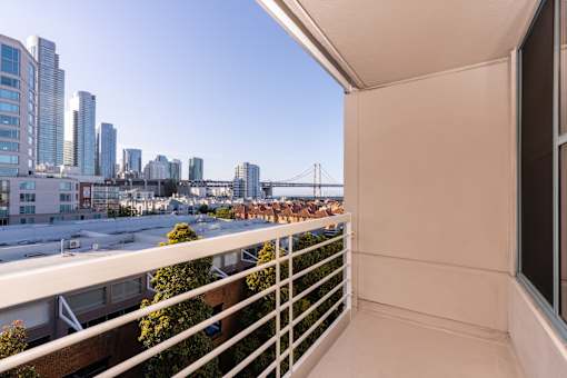 A balcony overlooks a cityscape with a bridge in the distance.
