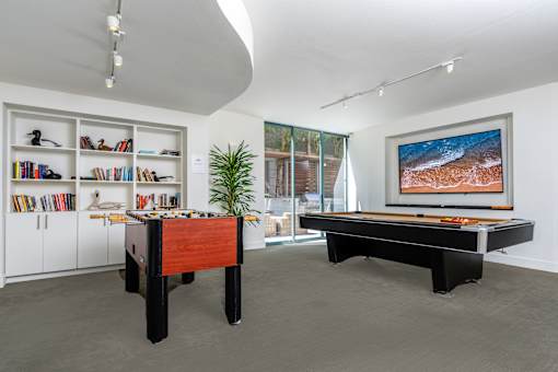 A room with a pool table and a bookshelf.