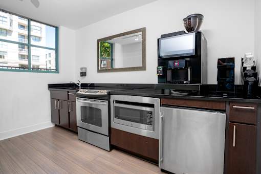 A modern kitchen with dark wood floors and stainless steel appliances.