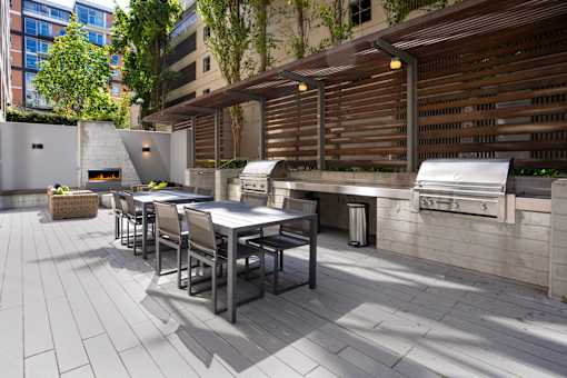 A patio with a table and chairs and a grill.