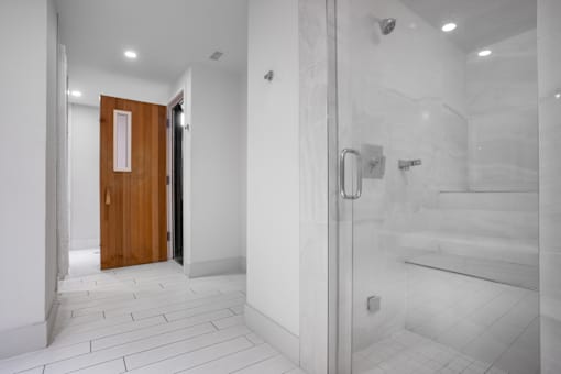 A white tiled bathroom with a wooden door.