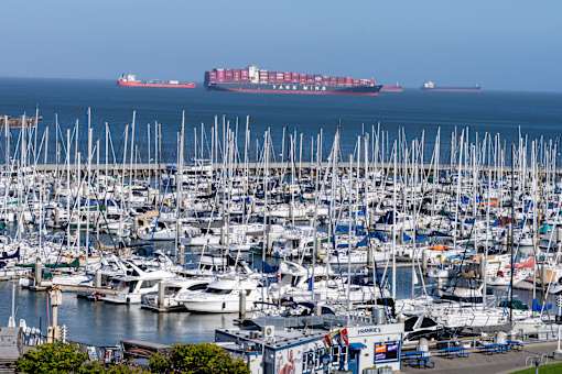 A large container ship is in the distance at a busy marina.