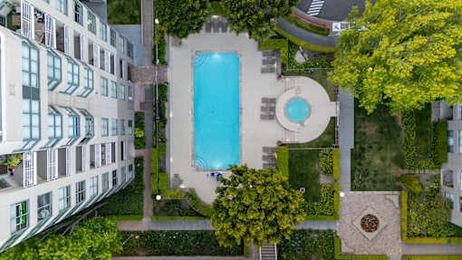 An aerial view of a pool surrounded by a building and trees.