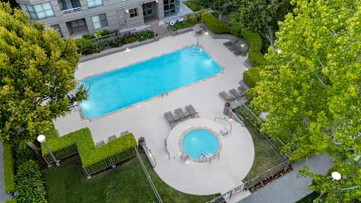A swimming pool surrounded by a grassy area and trees.