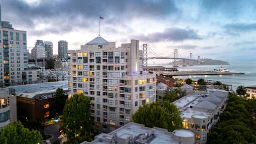 A cityscape with a bridge in the background and a building with a flag on top.