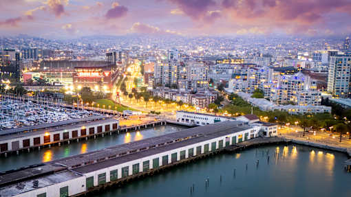 A cityscape at dusk with a marina in the foreground.