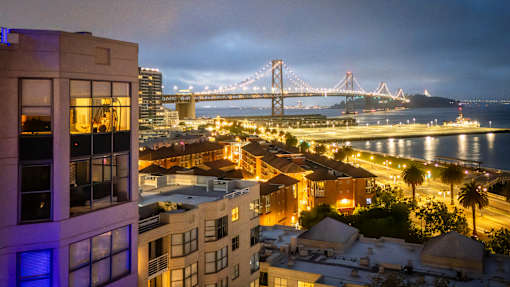 A cityscape at night with a bridge in the background.