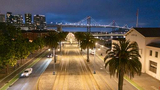 A city street at night with a bridge in the background.