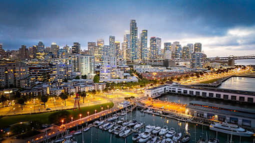 A cityscape at dusk with a marina full of boats.