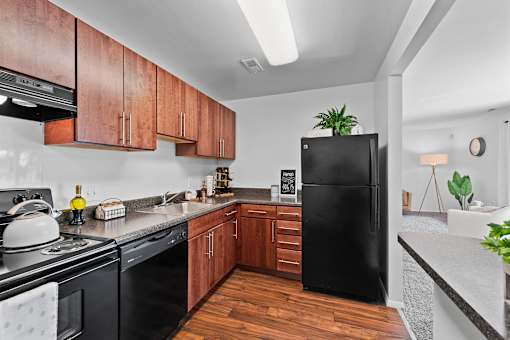 A black refrigerator stands in a kitchen with wooden cabinets and a black stove.