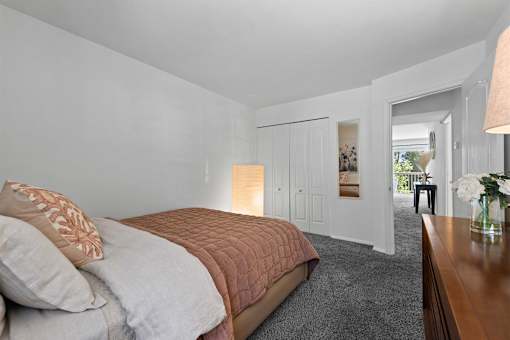A bedroom with a bed, a nightstand, and a window.