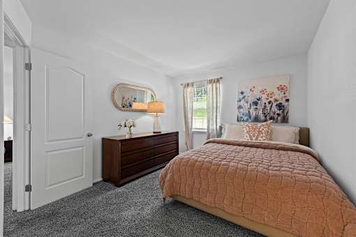 A bedroom with a bed, dresser, and mirror.