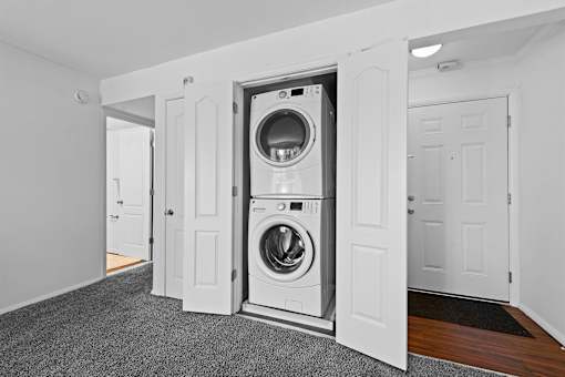 A white laundry room with a washer and dryer built into the wall.