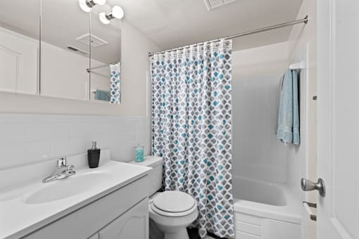 A white bathroom with a blue and white shower curtain.
