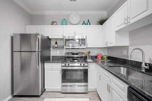 A modern kitchen with white cabinets and stainless steel appliances at The Grand Reserve at Tampa Palms Apartments, Tampa, 33647