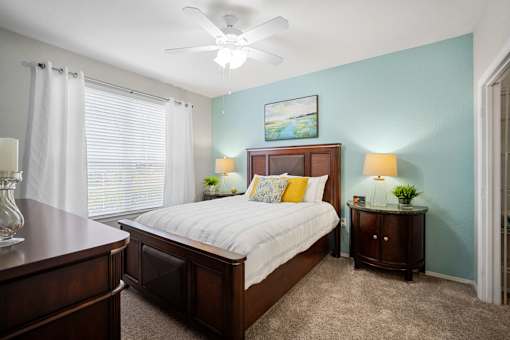A bedroom with a bed, nightstands, and a ceiling fan at The Grand Reserve at Tampa Palms Apartments, Tampa, FL, 33647
