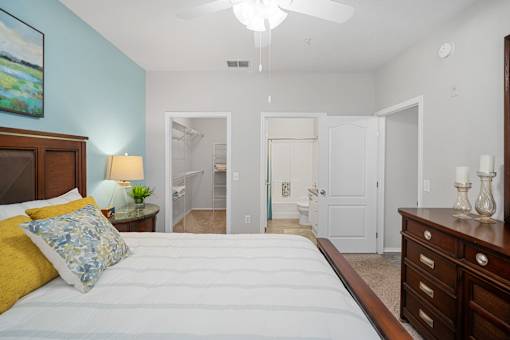 A bedroom with a bed, dresser, and a painting on the wall at The Grand Reserve at Tampa Palms Apartments, Tampa, 33647