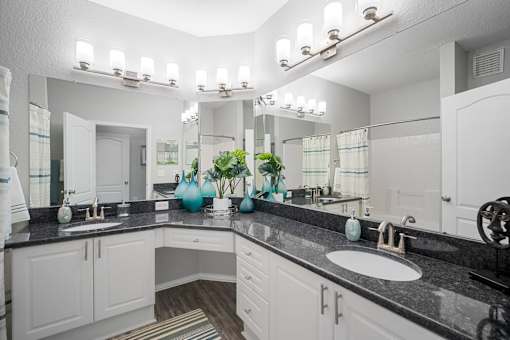 A bathroom with two sinks and a large mirror at The Grand Reserve at Tampa Palms Apartments, Tampa, Florida