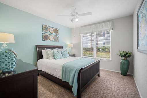 A bedroom with a bed, a ceiling fan, and a window with blinds at The Grand Reserve at Tampa Palms Apartments, Tampa, FL, 33647