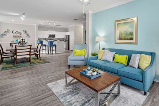 A living room with a blue couch and a coffee table at The Grand Reserve at Tampa Palms Apartments, Florida