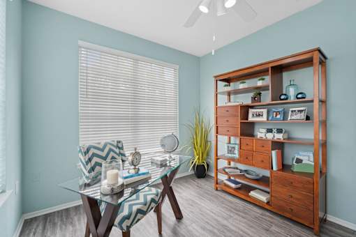 A room with a glass table and a wooden bookshelf at The Grand Reserve at Tampa Palms Apartments, Tampa, FL