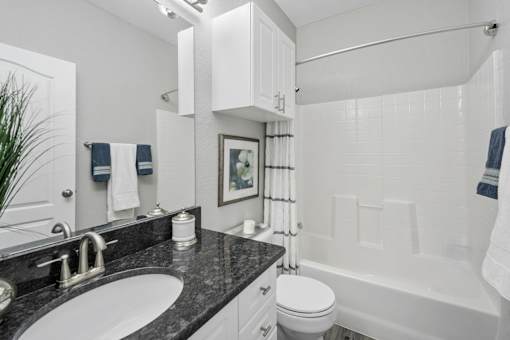 A bathroom with a white tub, sink, and toilet at The Grand Reserve at Tampa Palms Apartments, Florida