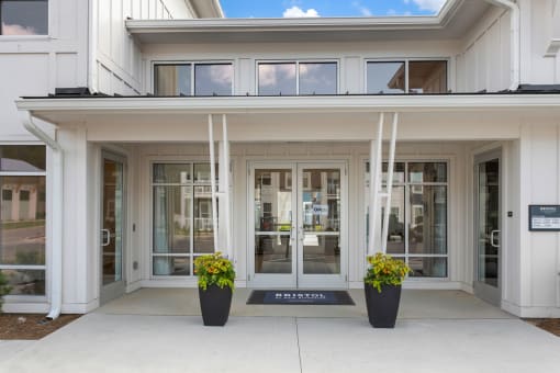 the front entrance of a building with glass doors and a sign on the sidewalk at Bristol at New Riverside, South Carolina