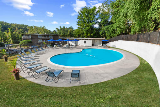 a pool with chairs and umbrellas around it at Brook View Apartments, Maryland