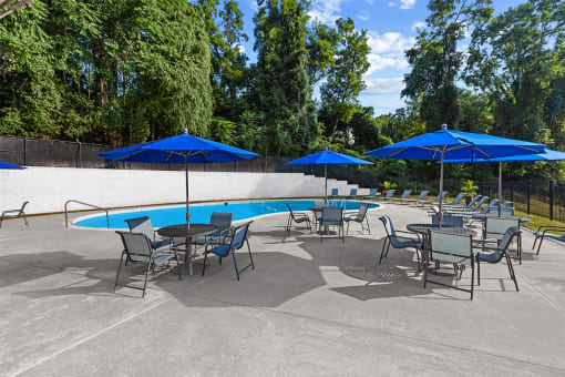 a group of tables with umbrellas and chairs around a pool at Brook View Apartments, 21209, MD