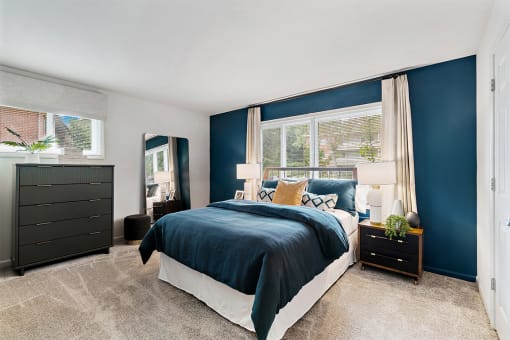 a bedroom with blue walls and a bed with a blue comforter at Falls Village Apartments, Baltimore