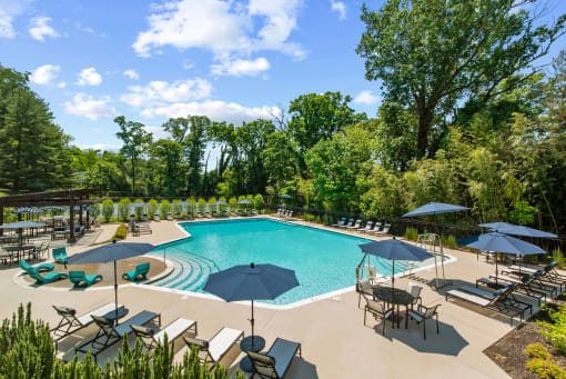 a swimming pool with umbrellas and chairs around it at Padonia Village Apartments, Timonium, 21093