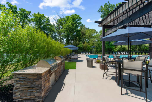 a patio with tables chairs and umbrellas and a pool at Padonia Village Apartments, Timonium, 21093