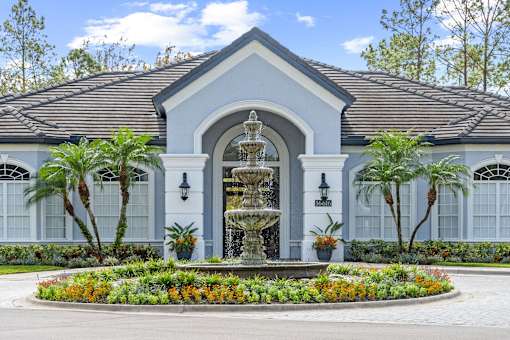 A white building with a fountain in front at The Grand Reserve at Tampa Palms Apartments, Tampa