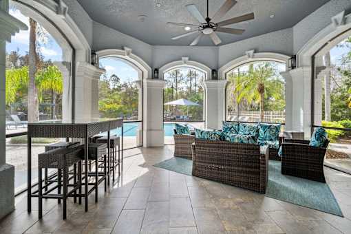 A patio with a table and chairs overlooking a pool at The Grand Reserve at Tampa Palms Apartments, Tampa
