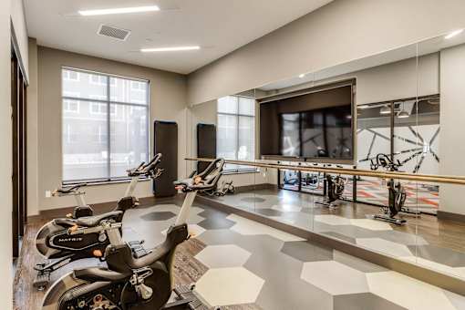 a workout room with bikes and a large screen on the wall at Dartmoor Place at Oxford Square Apartments, Hanover, MD