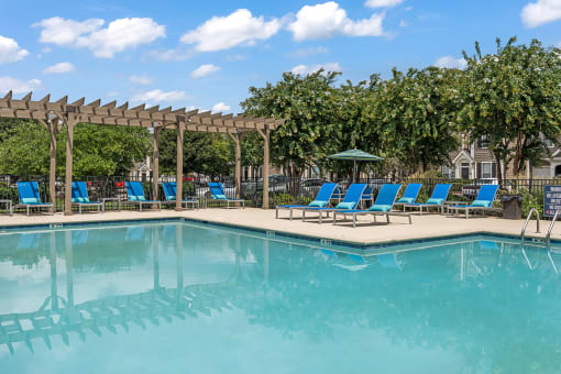 a swimming pool with blue chaise lounge chairs and a pergola with trees in the at Fortress Grove, Murfreesboro