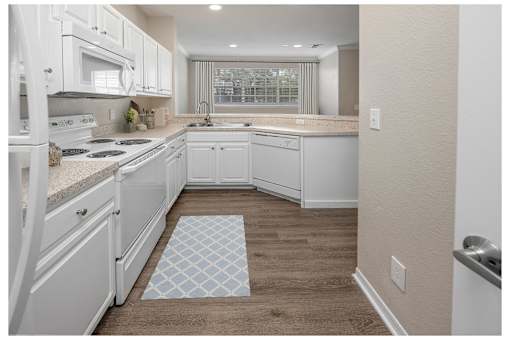 A kitchen with white cabinets and a tile floor mat at Henley Tampa Palms Apartments, Florida